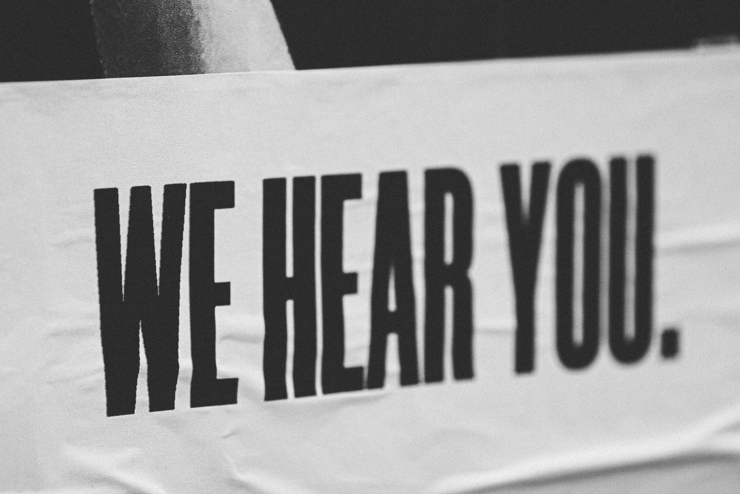 Black and white sign reading We hear you